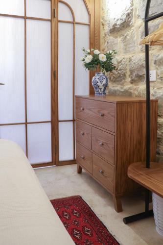 a bedroom with a dresser with a vase of flowers on it at Beyt El Midan in Ehden