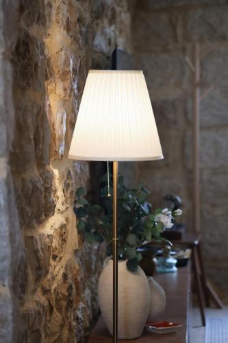 a table with a lamp and a vase with a plant at Beyt El Midan in Ehden