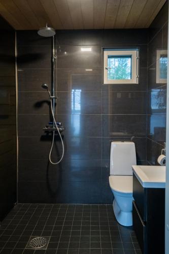 a bathroom with a shower with a toilet and a sink at Villa Kuulas in Sääskilahti