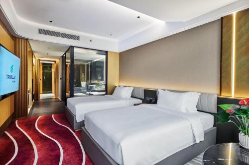 two beds in a room with a tv at TRIMULIA Hotel in Sihanoukville