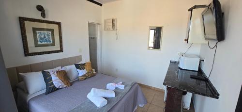 a small bedroom with a bed and a television at Pousada Mar Dos Anjos in Arraial do Cabo
