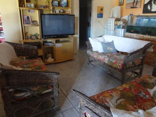 Pousada Sol e Mar في باراجورو: غرفة معيشة مع تلفزيون وأريكة وكراسي
