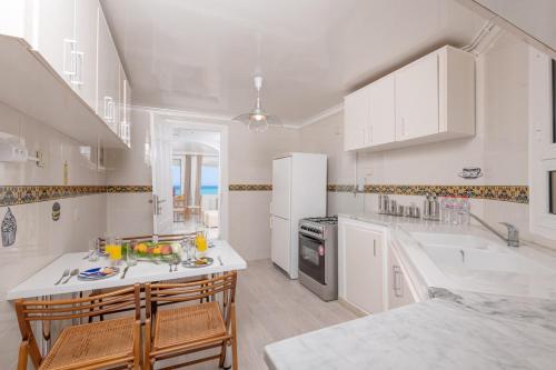a kitchen with white cabinets and a kitchen island with chairs at L'Horizon in Gammarth