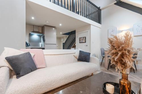 a living room with a white couch and a staircase at Cosy Mezzanine Apartment Leeds City Centre in Leeds