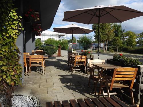 a patio with wooden tables and chairs and umbrellas at B&B HOTEL Regensburg-Ost in Regensburg