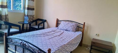 a bedroom with a bed and two chairs and a table at Cozy Guest Room in Kinshasa with Balcony and Partial Air-Conditioning in Lemba-Gaba