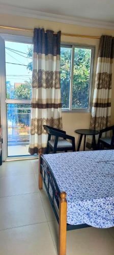 a bedroom with a bed and a large window at Cozy Guest Room in Kinshasa with Balcony and Partial Air-Conditioning in Lemba-Gaba
