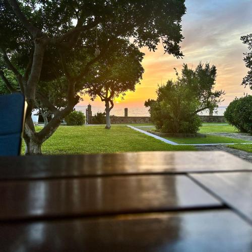 a bench in a park with a sunset in the background at Genari Beach Apartments Sea View Apartment for Couples or Small Families in Korakokhórion