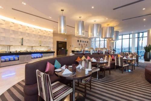a restaurant with tables and chairs and a bar at Holiday Inn Abu Dhabi by IHG in Abu Dhabi