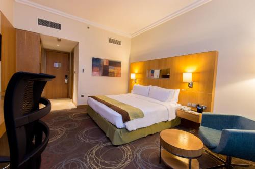 a hotel room with a large bed and a chair at Holiday Inn Abu Dhabi by IHG in Abu Dhabi