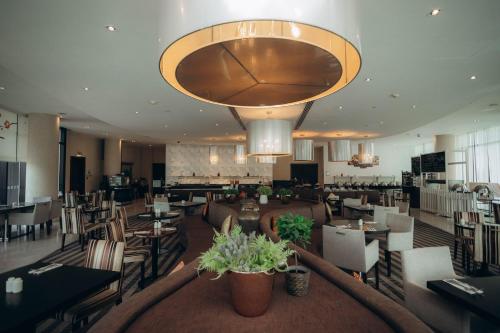 a restaurant with tables and chairs and a large chandelier at Holiday Inn Abu Dhabi by IHG in Abu Dhabi