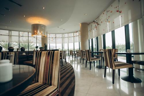 a dining room with chairs and tables and windows at Holiday Inn Abu Dhabi by IHG in Abu Dhabi