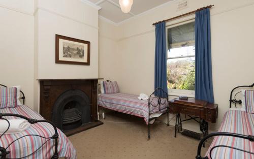 a bedroom with two beds and a fireplace and a window at Abaleen House in Queenscliff