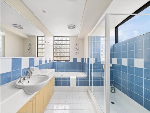 a bathroom with blue tiles and a sink and a tub at Beachside Getaway - Family Villa at Sebel Resort in Broadwater