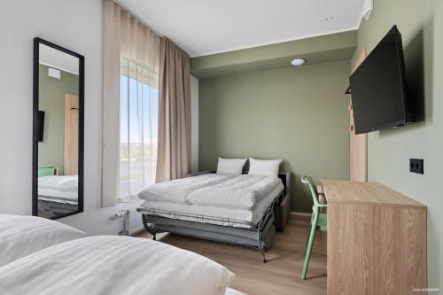 a bedroom with a bed and a mirror and a tv at Aiden by Best Western Odense in Odense