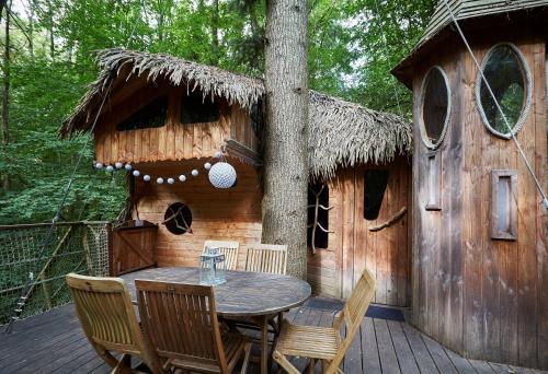 a patio with a table and chairs and a tree at Cabanes de la Grande Noe in Les Épasses