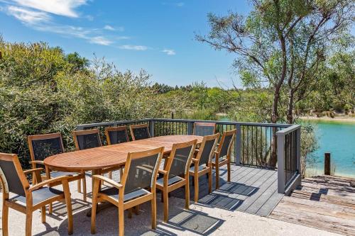 a wooden table and chairs on a deck with water at Bonnie and Piper - Lakeside and Wine Country Living in Wilyabrup
