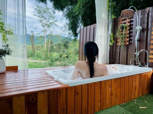a woman sitting in a bath tub with a window at เฮือนป้อหลวง in Ban Fang