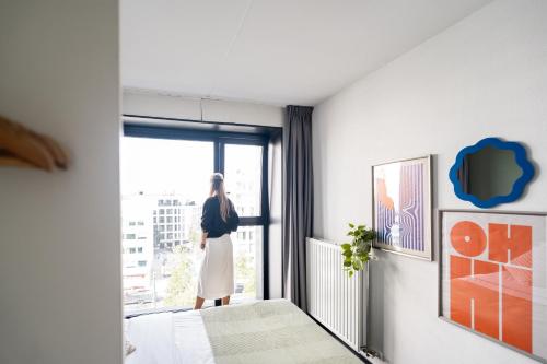 a woman standing in a room looking out the window at The ASH in Antwerp