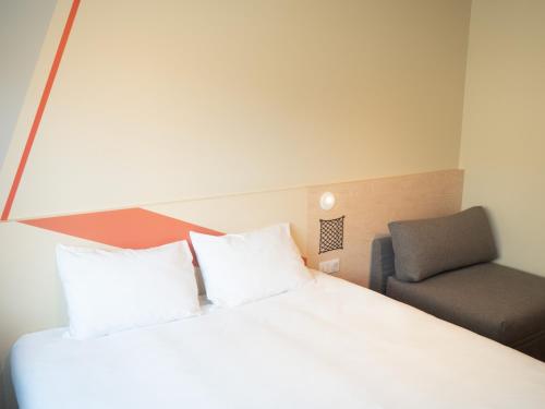 a bedroom with a white bed and a chair at Ibis Budget Saint Malo Centre in Saint Malo