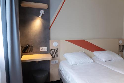 a bedroom with two beds and a desk and a bed sidx sidx sidx at Ibis Budget Saint Malo Centre in Saint Malo