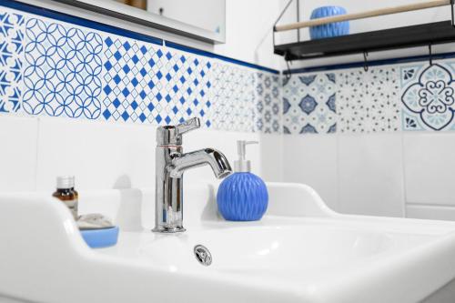 a bathroom sink with a blue and white tiles at Madárdalos Kert és Vendégház in Tokaj