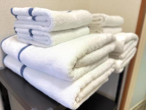 a stack of white towels sitting on a shelf at Mokuga apartment in Tokyo