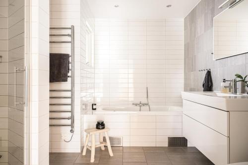 a white bathroom with a tub and a sink at Villa med privat läge nära Elmia in Huskvarna
