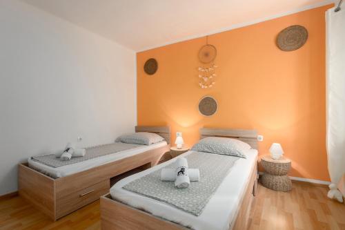 two twin beds in a room with orange walls at Casa Nadia in Mošćenička Draga