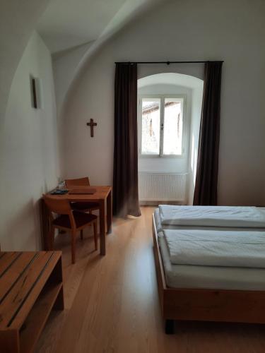 a bedroom with a bed and a table and a window at Gästehaus Benediktinerstift Göttweig - Bed & Breakfast Monastery in Furth