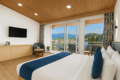 a hotel room with a large bed and a balcony at Central Heritage Resort & Spa Formerly Fortune ITC Resort in Darjeeling