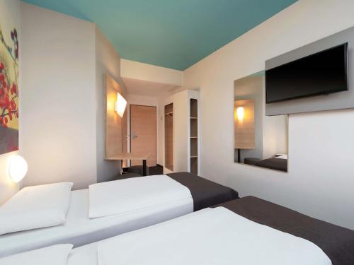 a hotel room with two beds and a flat screen tv at B&B Hotel Potsdam in Potsdam