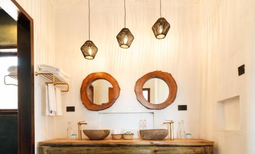 a bathroom with two sinks and two mirrors at Escarpment Luxury Lodge Manyara in Mto wa Mbu