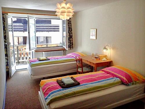 a room with two beds and a table and a window at Arturo Fasciati Ferienwohnungen in Bivio