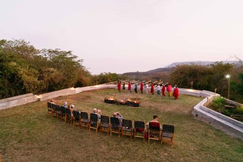 a group of people sitting in chairs watching a performance at Escarpment Luxury Lodge Manyara in Mto wa Mbu