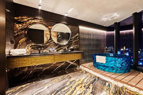 a bathroom with a tub and two mirrors at TRIMULIA Hotel in Sihanoukville