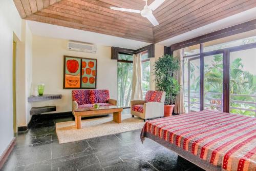 a bedroom with a bed and chairs and a ceiling fan at Casa Colvale in Mapusa