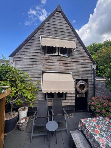 a house with two chairs and a table and a grill at Tiny House Lindenhouse in Heemstede