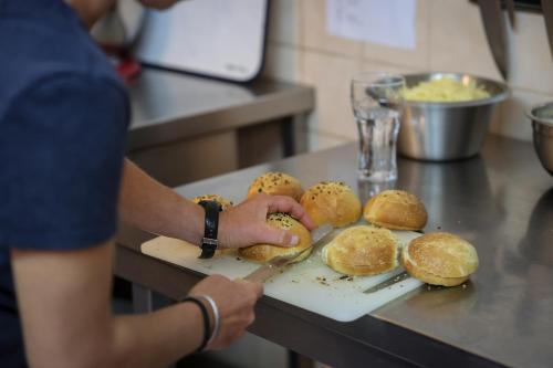 a person cutting buns on a cutting board with a knife at Hôtel Restaurant Gîtes Les 5 Saisons in Freissinieres