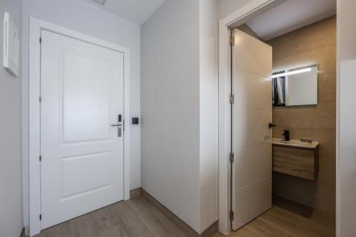 La salle de bains est pourvue d'un lavabo et d'une porte blanche. dans l'établissement Habitaciones San Bernardo, à Madrid