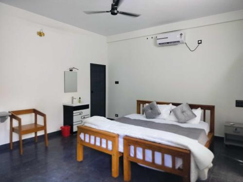 a bedroom with a bed and a desk and a chair at Hotel O Nemom Formerly Ambadi Guest House in Poojapura