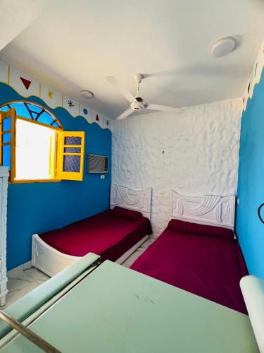 Una pequeña habitación con dos camas y una ventana. en Tongel Nubian Studio & Guest House, en Asuán