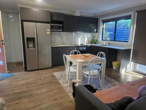 a kitchen with a table and chairs and a kitchen with a refrigerator at Oasis in the Heart of Dural in Dural