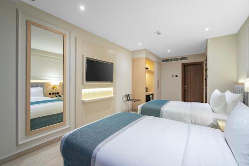 a hotel room with two beds and a television at Grand Ambassador Hotel in Dubai