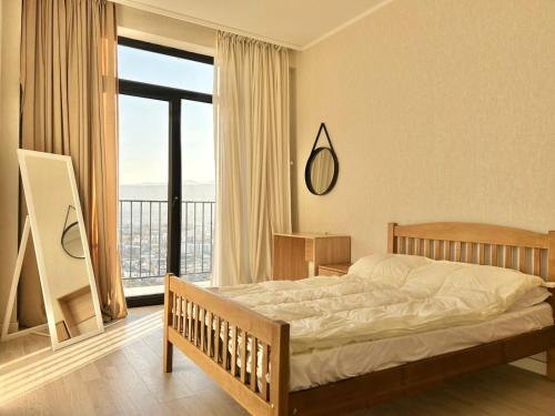 a bedroom with a bed and a large window at Sunny apartment in Tbilisi City