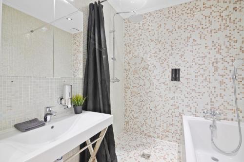 Un baño con lavabo, bañera y ducha. en Arc de Triomphe - Luxurious 3 Bedroom with NetFlix, en París