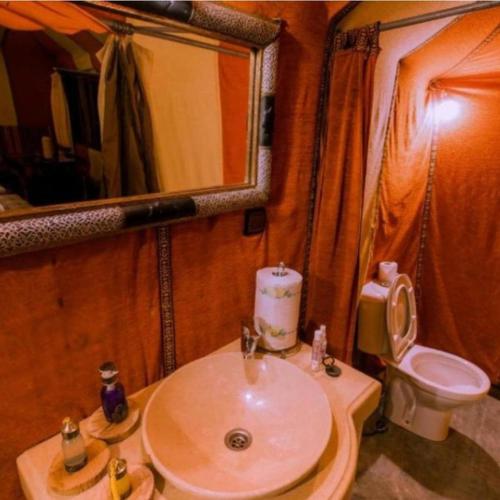 a bathroom with a sink and a toilet and a mirror at Yamanda luxury camp in Merzouga