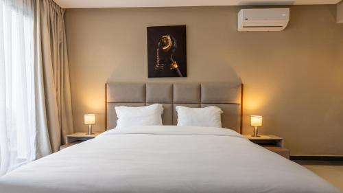 a bedroom with a large white bed with two lamps at PLAYA DEL PACHA Suites Hotel in Marina Smir