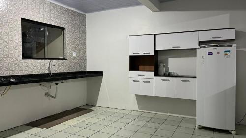 a kitchen with white cabinets and a refrigerator at Casa da folha 12 in Marabá