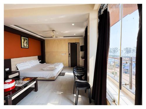 a bedroom with a bed and a table and a balcony at BIG বিগ বস Boss Front The New Digha Sea Beach in Digha